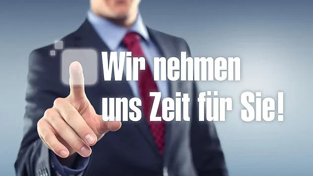 Mann zeigt auf den Schriftzug "Wir nehmen uns Zeit für Sie!" auf einer transparenten Glasfront.